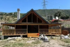 Uzak çekim arkası dağ olan beşik çatı önü verandalı 150 m2 Ağaç tomruk ev