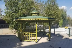 Site içersinde yeşillikler içinde yeşil renkli sekizgen ahşap kamelya