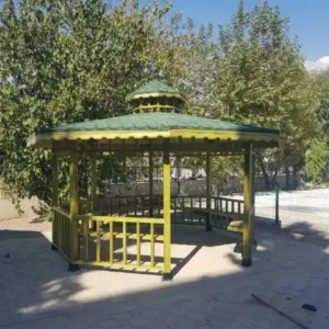 Site içersinde yeşillikler içinde yeşil renkli sekizgen ahşap kamelya