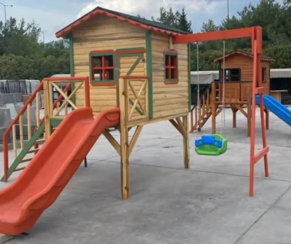 Turuncu renkte kaydırak ve yanında yeşil salıncağı olan yerden yüksek küçük çocuk oyun evi