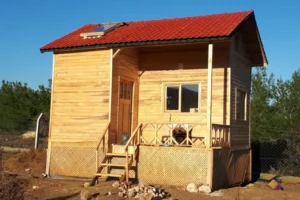 Kırmızı çatısı olan önünde verandası ile iki katlı küçük 20 m2 bungalov ev