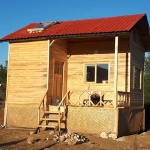 Kırmızı çatısı olan önünde verandası ile iki katlı küçük 20 m2 bungalov ev
