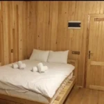 Ahşap duvarlı beyaz çarşaflı çift kişilik ahşap oda yatak modeli