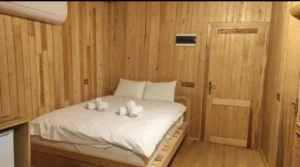 Ahşap duvarlı beyaz çarşaflı çift kişilik ahşap oda yatak modeli