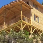 Yerden çekilmiş iki katlı önü verandalı ve yuvarlak ayaklı ahşap ev